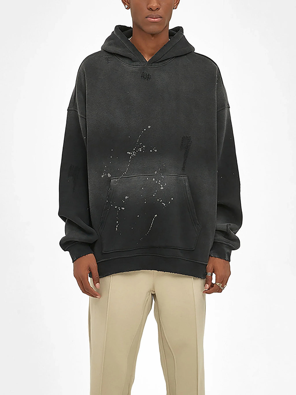 Black oversized streetwear hoodie with paint splatter design, paired with beige pants