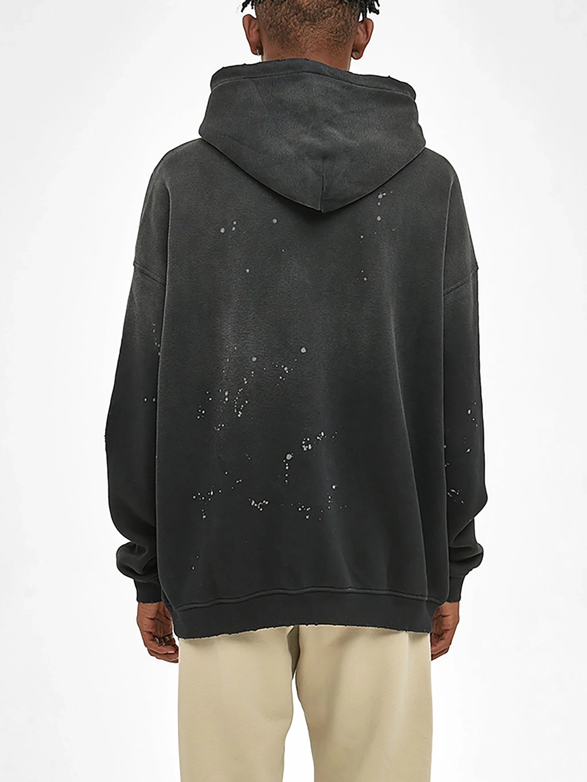 Back view of oversized black hoodie with paint splatter details, urban streetwear style